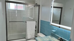Ein Badezimmer mit Badewanne, Toilette, Waschbecken und Spiegel.