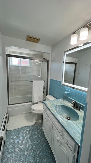 Ein Badezimmer mit Badewanne, Toilette, Waschbecken und Spiegel.