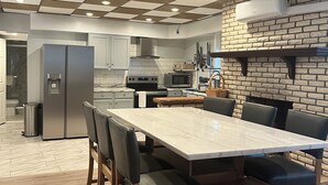 Eine moderne Küche mit Marmorarbeitsplatte, Edelstahlgeräten und einer Karokku-Decke.