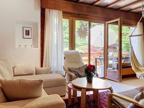 A cozy living room with a sofa, armchair, and a round table with a vase of flowers.