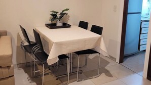 A dining area with a table set for four, surrounded by chairs, a potted plant, and a sofa. - Recoleta Apartment with a Spacious Patio (Buenos Aires)