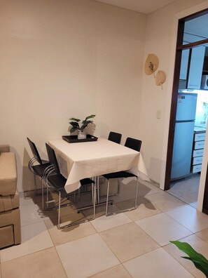 A dining area with a table set for four, surrounded by chairs, a potted plant, and a sofa. - Recoleta Apartment with a Spacious Patio (Buenos Aires)