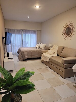 A modern bedroom with a bed, a sofa, a television, and a large plant. - Recoleta Apartment with a Spacious Patio (Buenos Aires)