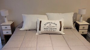 A bed with a beige quilted bedspread, two white pillows, and two bedside tables with lamps. - Recoleta Apartment with a Spacious Patio (Buenos Aires)