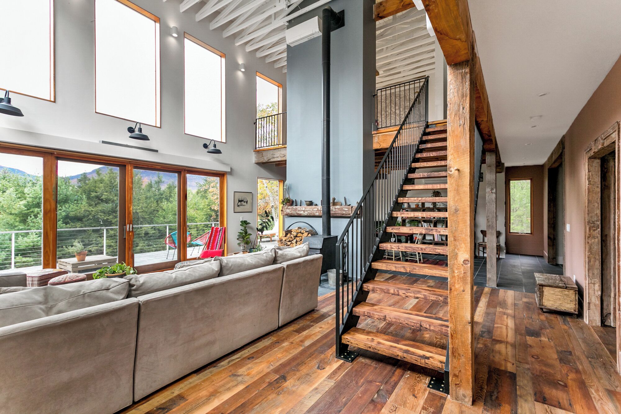 A spacious living area with a large window, a wooden staircase, and a built-in bench.