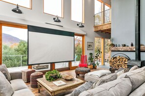 Een ruime woonkamer met een groot raam, een open haard en een balkon.
