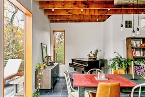 A dining area with a piano, a table, chairs, and a bookshelf. - The Windbourne A Luxury Retreat In The Catskills (Saugerties)