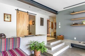A modern interior with a sliding barn door, a staircase, and a seating area with a patterned cushion. - The Windbourne A Luxury Retreat In The Catskills (Saugerties)