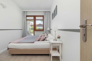 Ein Schlafzimmer mit Bett, Nachttisch, Lampe und Blick ins Freie.