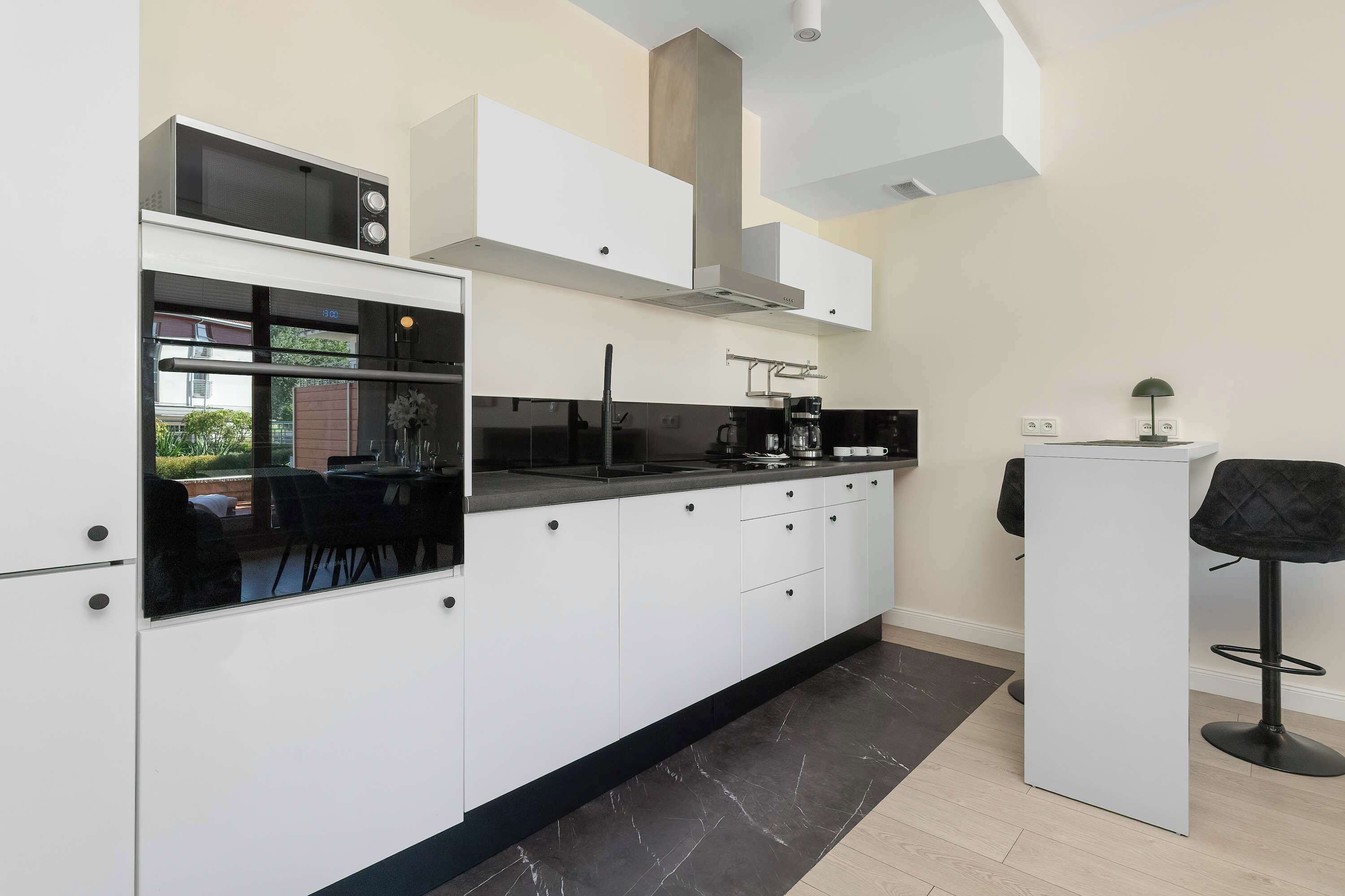 A modern kitchen with white cabinetry, a black countertop, and a built-in microwave.