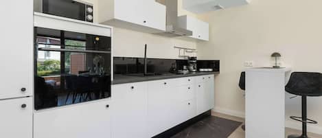 A modern kitchen with white cabinetry, a black countertop, and a built-in microwave.