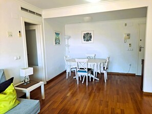 Een kamer met een eettafel, stoelen, een bank en een lamp.