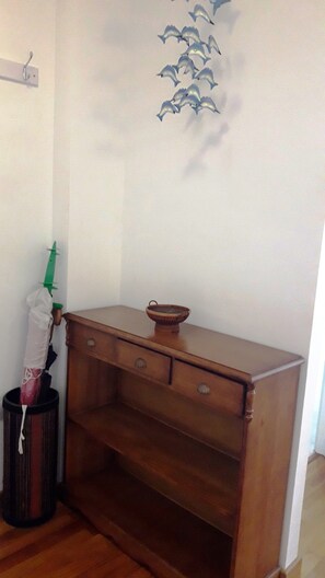 Eine Ecke eines Raumes mit einem Holzkasten, einem Mülleimer und einer Wanddekoration von Delfinen.