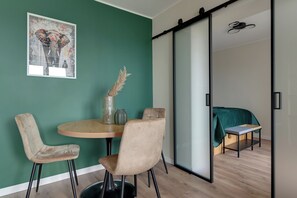 A modern interior with a dining area featuring a round table, two chairs, and a vase with dried plants. - Gdansk Riverside - Kamienna Grobla 24  (Gdańsk)