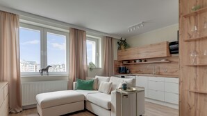 Una sala de estar moderna con un sofá modular, una mesita auxiliar y vistas a la ciudad a través de amplios ventanales.