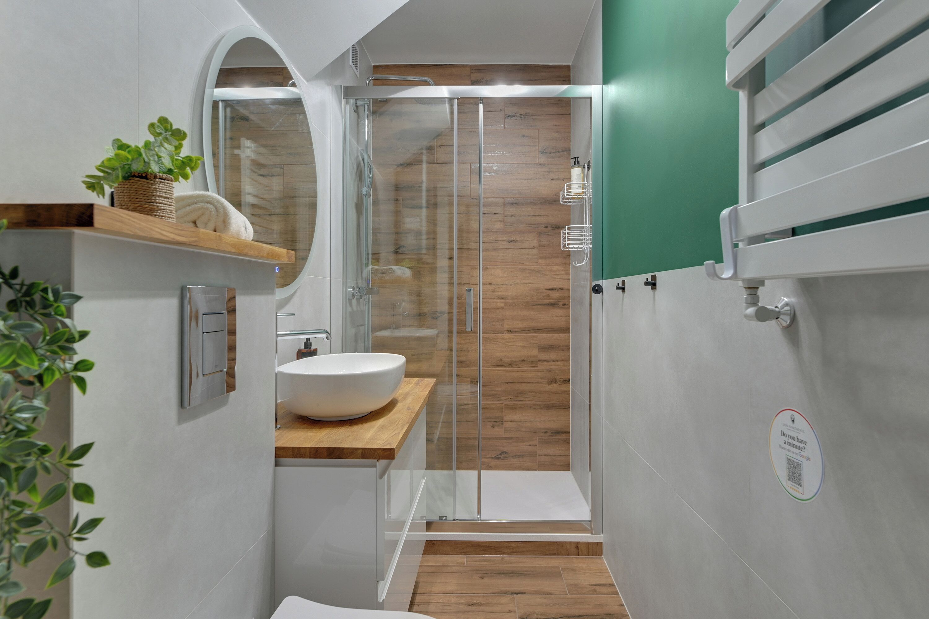 A compact bathroom with a white sink, wooden vanity, and a glass shower enclosure.