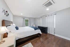 Ein modernes Schlafzimmer mit Bett, Nachttisch, Kommode und einer dekorativen Wandgestaltung.