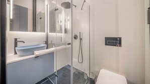 Un baño moderno con ducha de vidrio, un lavabo con recipiente y un espejo sobre el lavabo.