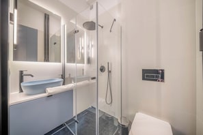 A modern bathroom with a glass-enclosed shower, a sink with a vessel basin, and a mirror above the sink. - Apartment Żelazna 58 (Warszawa)