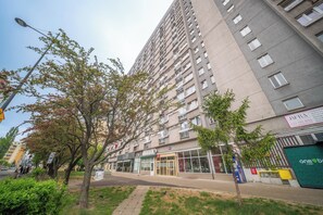 Ein mehrstöckiges Gebäude mit Eingangsbereich auf Straßenniveau und einer sichtbaren Schaufensterfront, bewölkter Himmel.