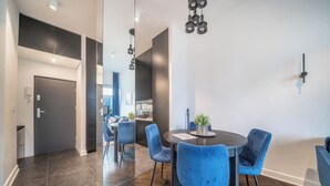 Un comedor moderno con una mesa redonda y sillas azules, piso de madera oscura e iluminación colgante en el techo.