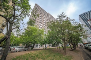 A tall residential building with multiple balconies, surrounded by trees and parked cars. - Apartment Żelazna 58 (Warszawa)