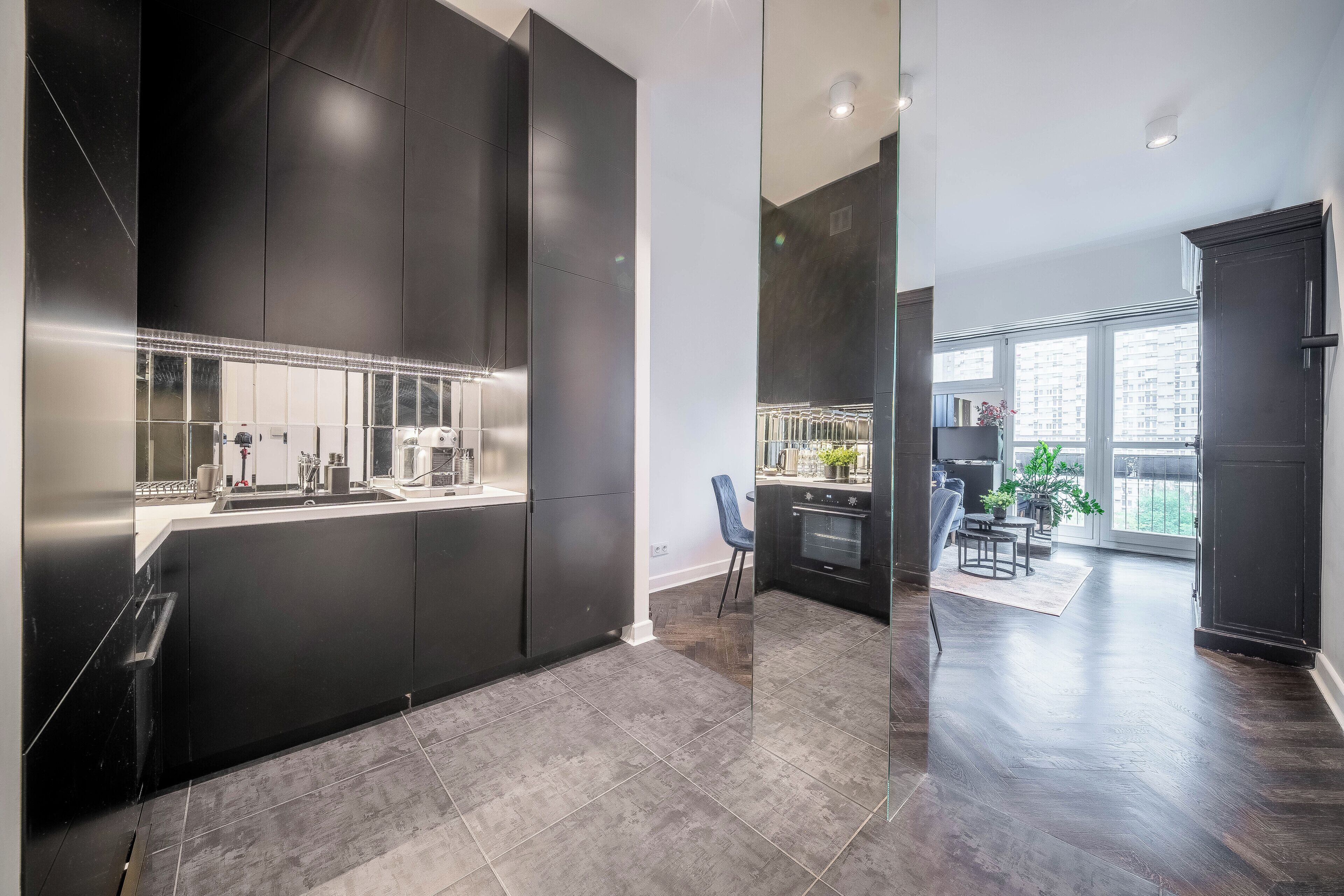 A modern kitchen with dark cabinetry, a stainless steel refrigerator, and a built-in oven.