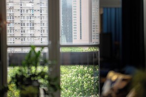 A view through a window with a building in the background and a green area in the foreground. - Apartment Żelazna 58 (Warszawa)