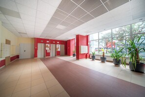 Eine großzügige Lobby mit rotem und beigefarbenem Farbschema, Fliesenboden und Zimmerpflanzen.