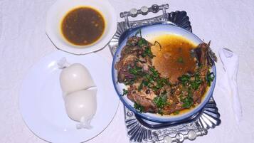 A plate of food with a bowl of sauce and a white item on a table.