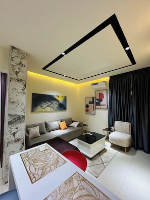 A modern living room with a sofa, coffee table, and a chair. - Benysta Hotel And Suites (Gwarinpa)