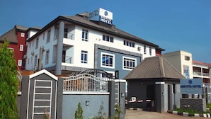 Un hotel con un letrero llamativo, entrada con portón y zona de espera cubierta.