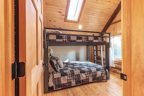 A bunk bed with a plaid quilt, a window with a view, and a skylight. - Lakefront Log Cabin | Private Dock, Beach, Firepit (Curtis)