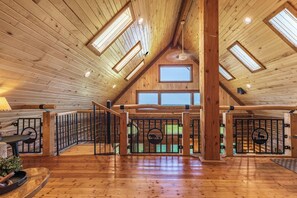 A spacious attic room with wooden floors, a loft-style staircase, and skylights.