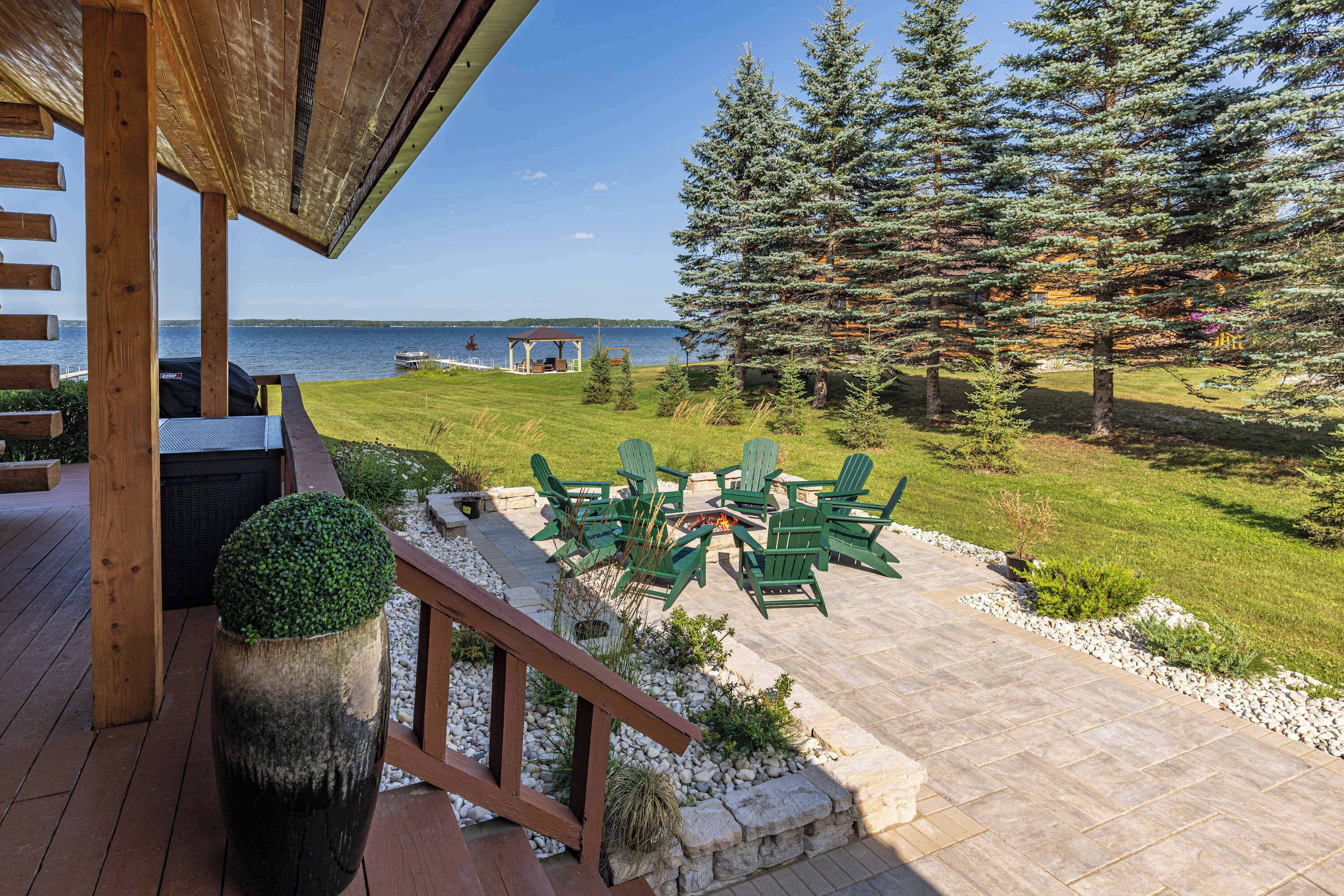 Eine Terrasse mit Sitzgelegenheiten im Freien, einer Feuerstelle und Blick auf den See.