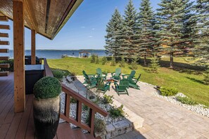 Une terrasse avec coin salon extérieur, un foyer et vue sur le lac.
