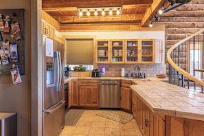 A modern kitchen with wooden cabinetry, stainless steel appliances, and a built-in dishwasher.