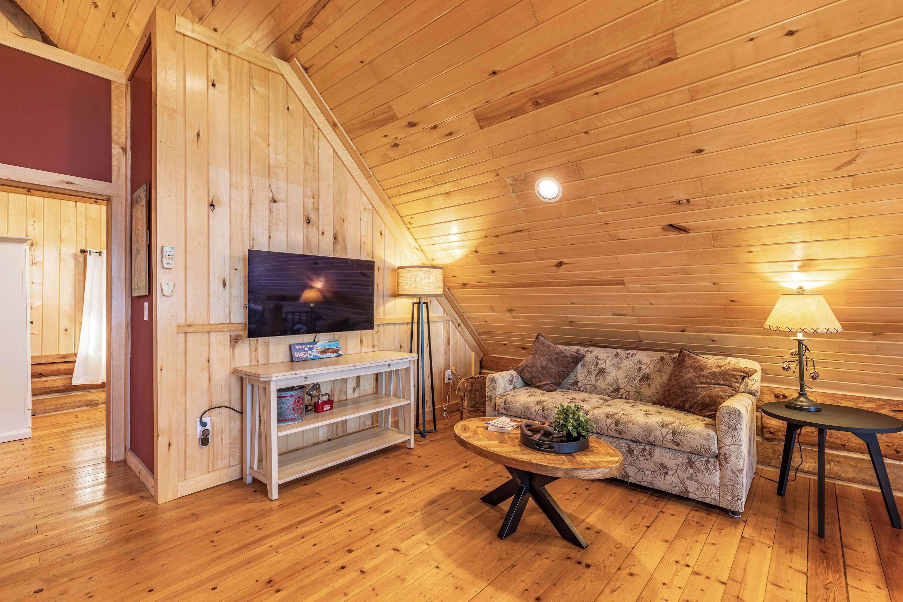 A cozy wooden interior with a sofa, a television, and a coffee table.