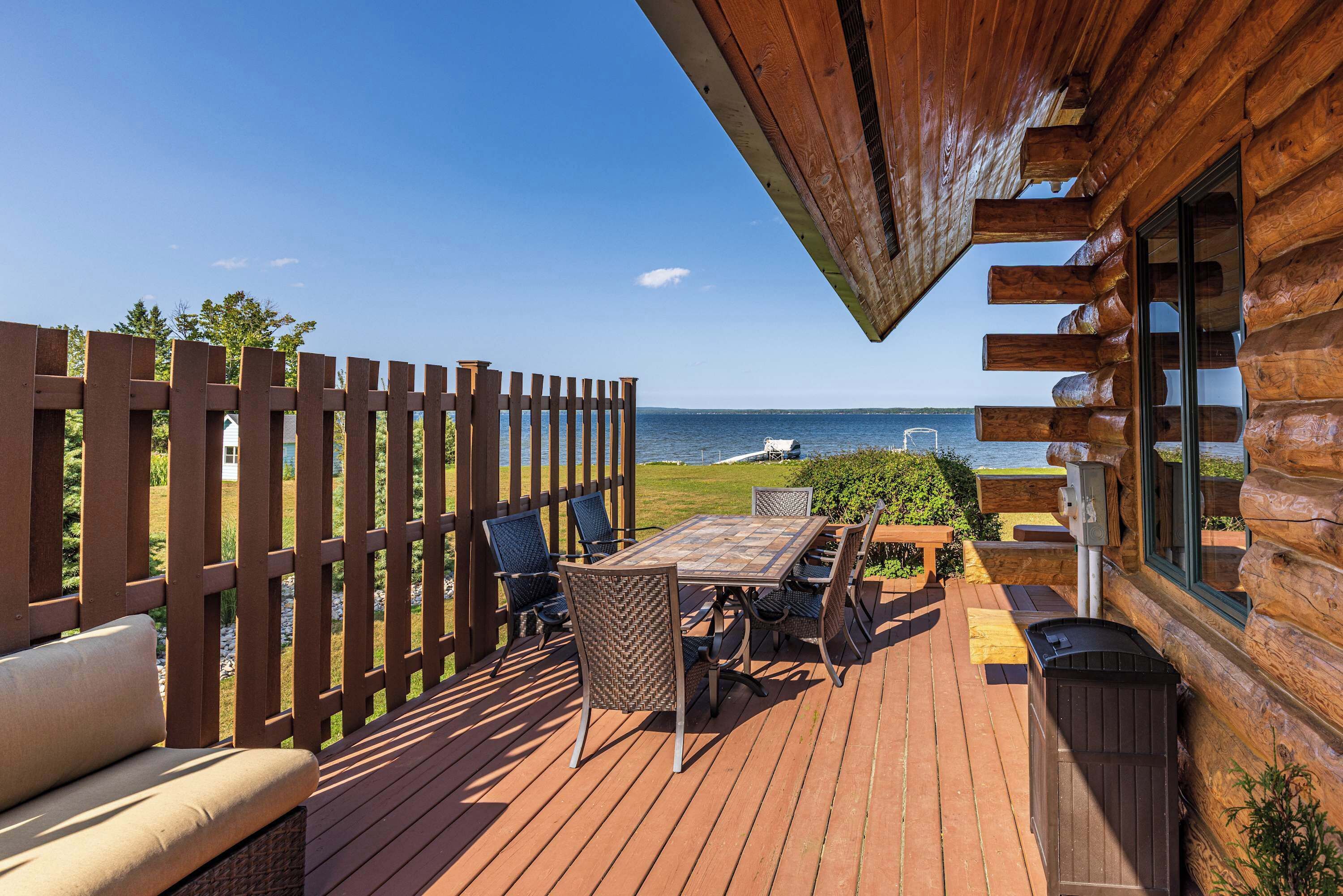 A wooden deck with a table and chairs, overlooking a body of water.