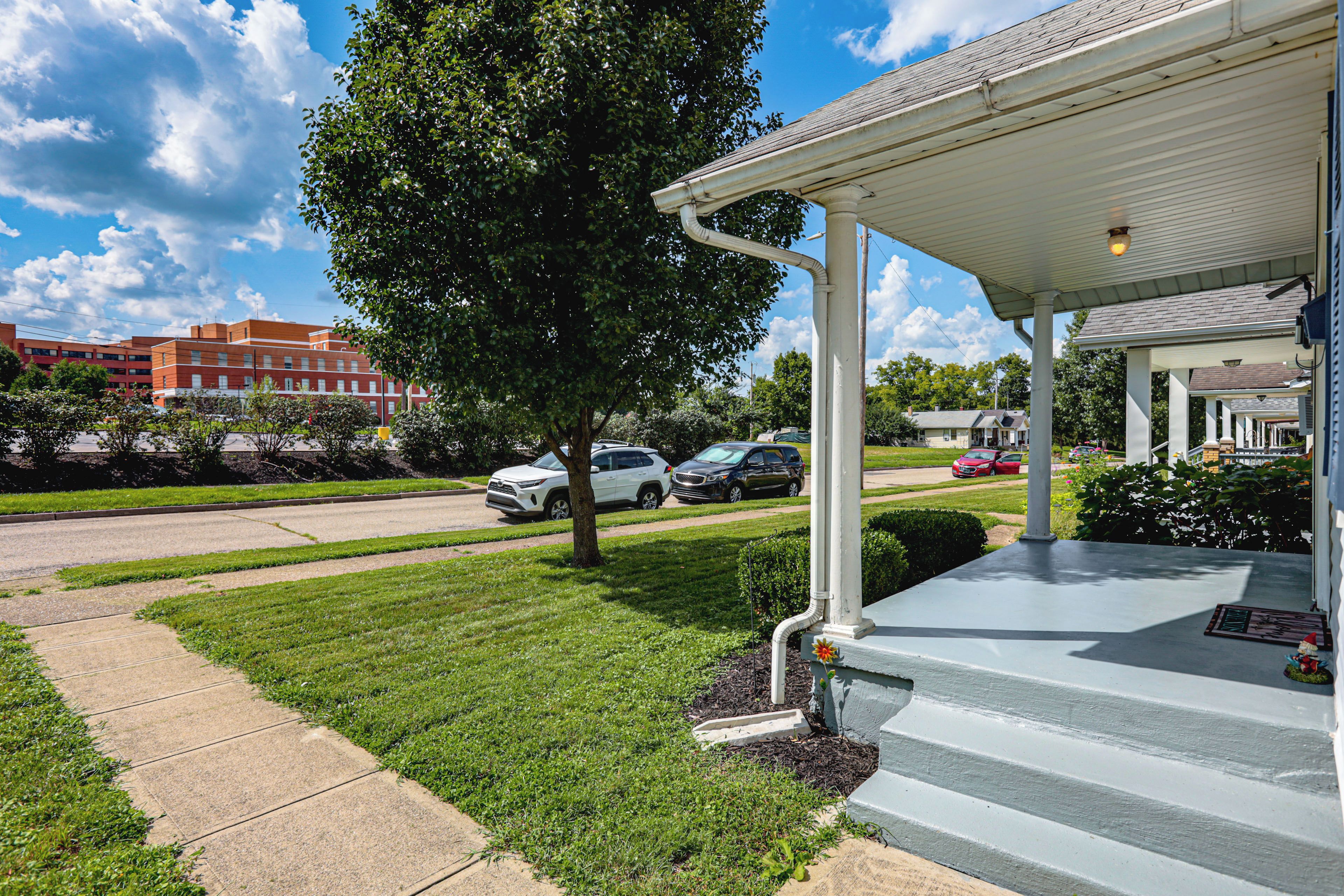 A building with a covered porch and a tree in front.