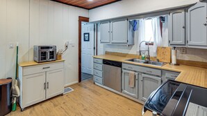 Eine Küche mit weißen Schränken, einer Holzausziehtafel, einem Geschirrspüler und einer Mikrowelle.