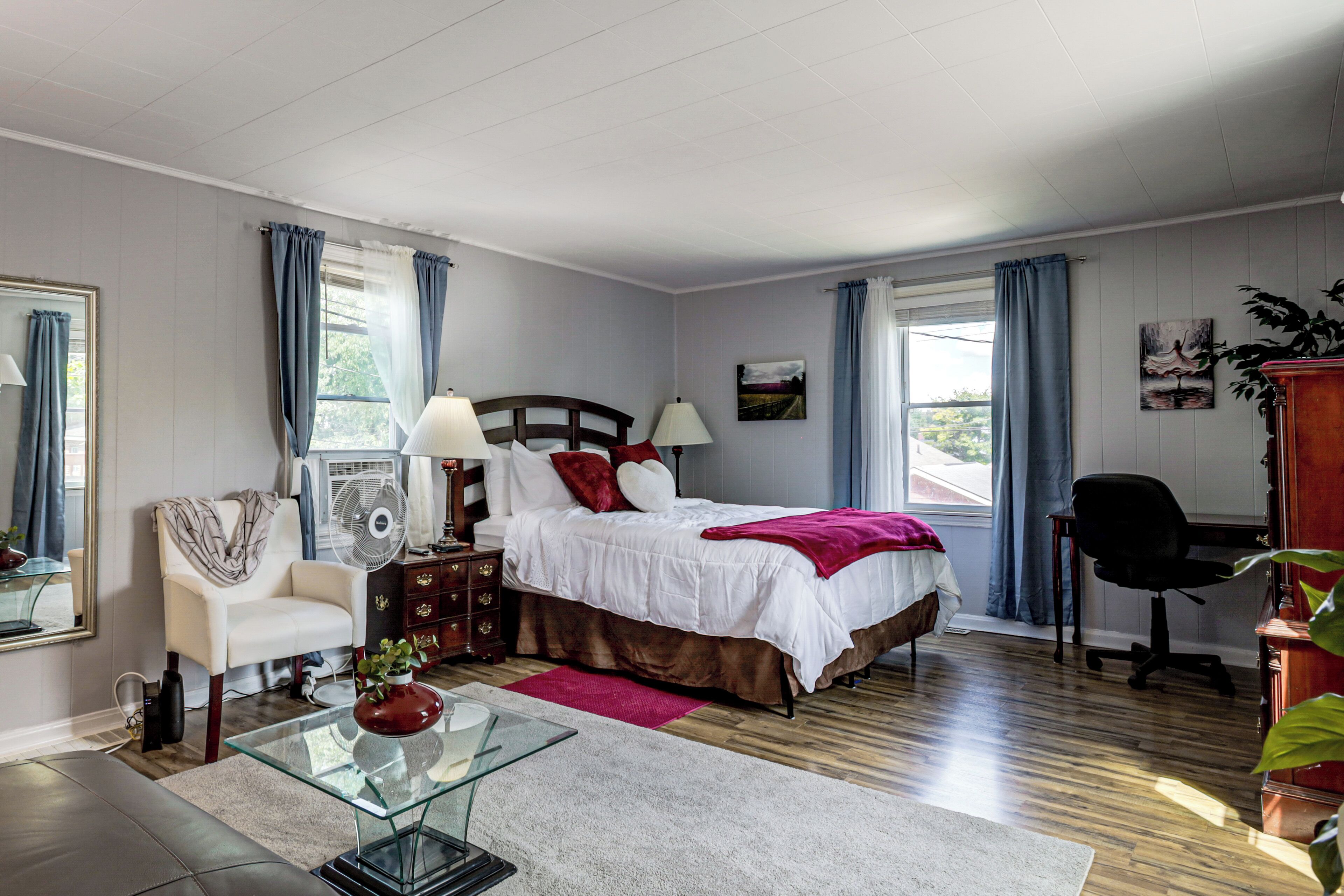 A bedroom with a bed, bedside tables, a chair, a desk, and a window with curtains.