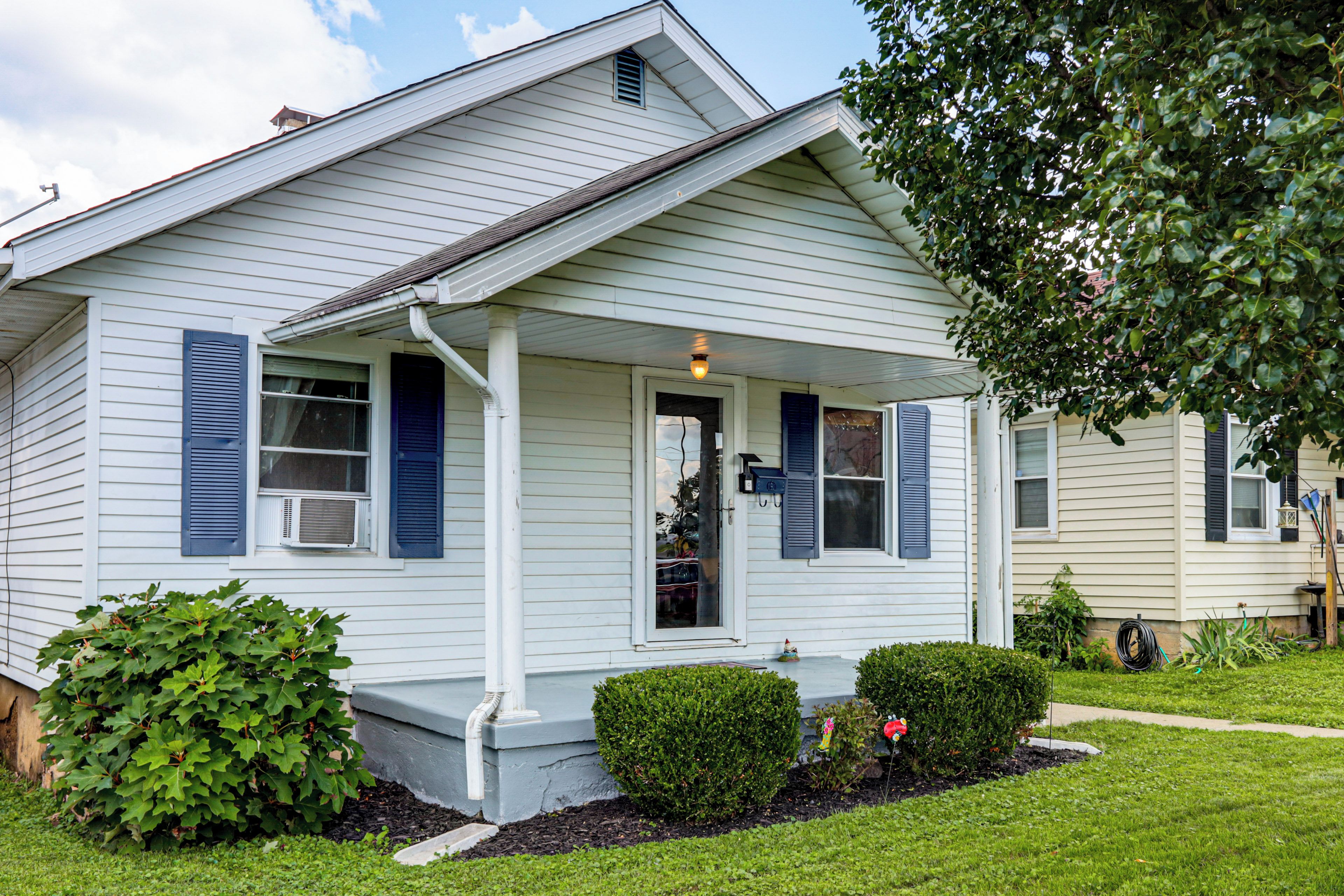 A single-story house with a front porch, a small garden, and a visible mailbox.