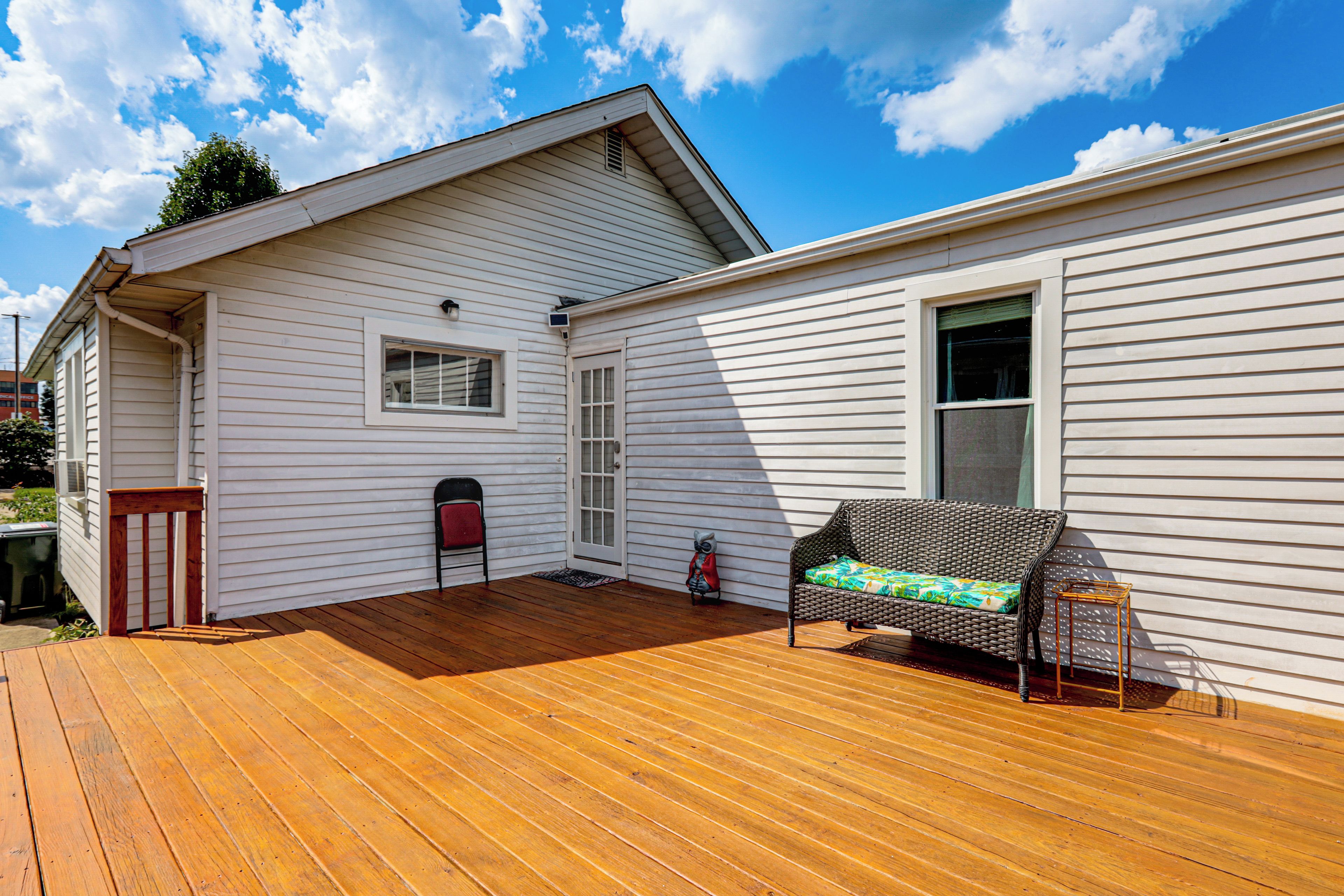 A house with a wooden deck, a bench, and a mailbox.
