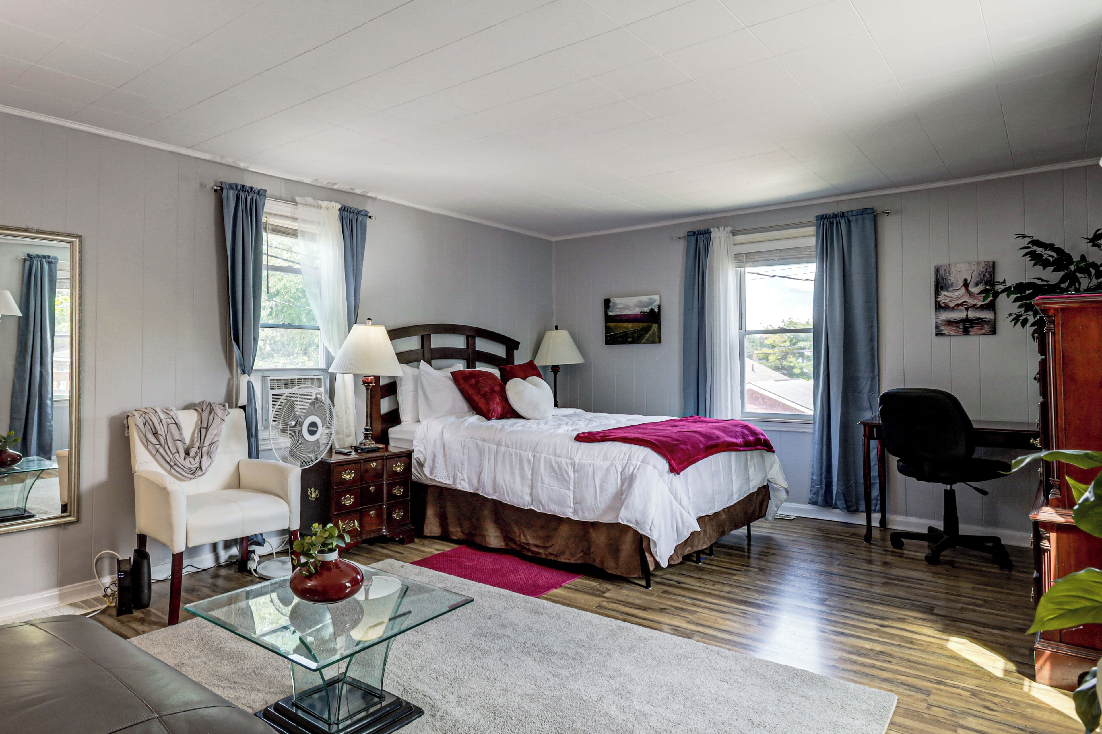 A bedroom with a bed, bedside tables, a chair, a desk, and a window with curtains.