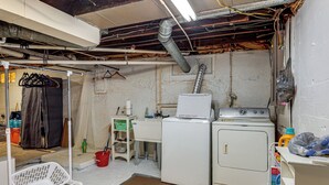 Ein Waschraum mit Waschmaschine, Trockner und verschiedenen Reinigungsmitteln.