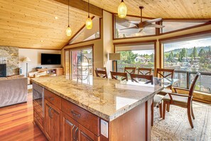 A spacious kitchen with a large island, wooden cabinets, and a dining area with chairs and a table. - Dock + Hot Tub! Waterfront Lake Tahoe Getaway (South Lake Tahoe)