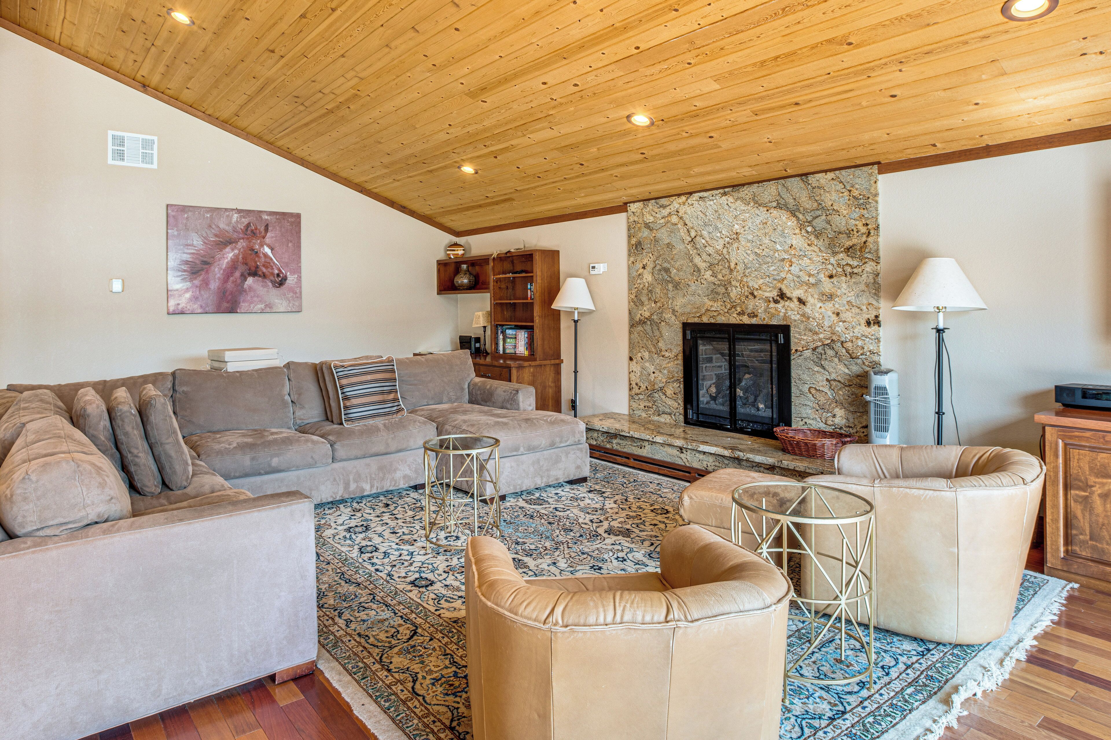 A spacious living room with a fireplace, a large sofa set, and a stone accent wall.