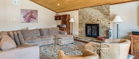 A spacious living room with a fireplace, a large sofa set, and a stone accent wall.