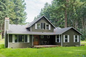 Une maison à deux étages avec un porche à l’avant, de grandes fenêtres et une cheminée.